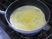 砂糖、塩を入れて混ぜた卵を薄焼きに焼いている写真